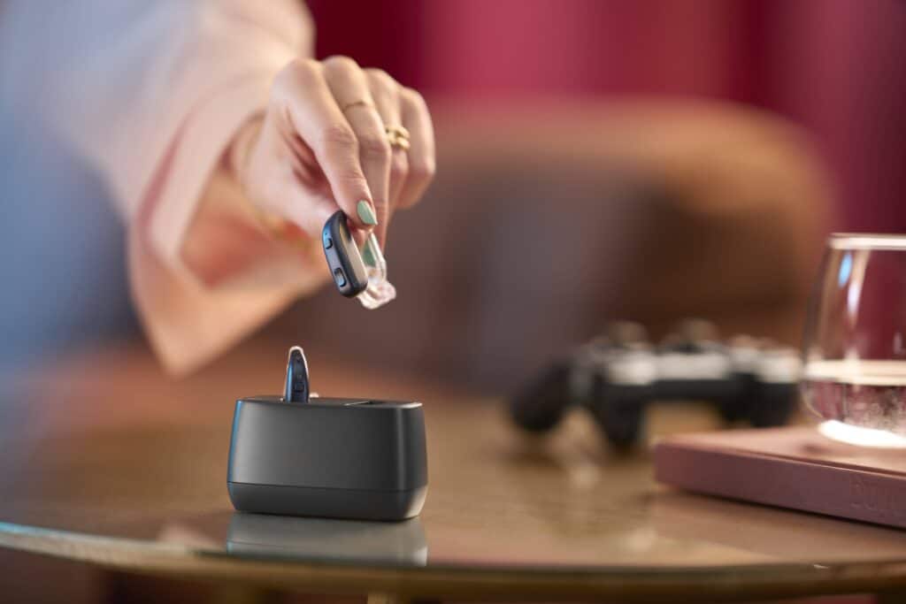 woman putting ReSound Enzo IA Super Power rechargeable hearing aid in case.