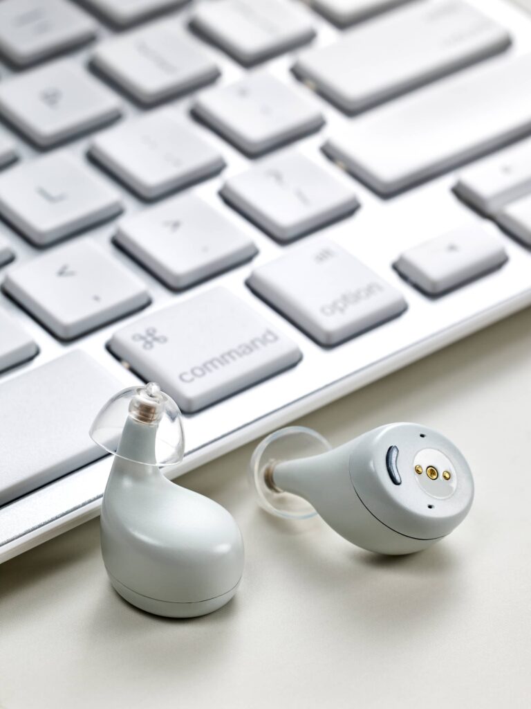 Techmi Match OTC hearing aids in white shown next to a computer keyboard
